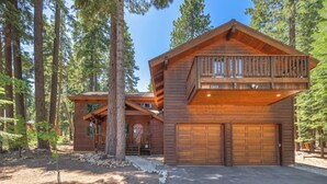 A wooden cabin with a balcony, a garage, and a stone pathway. - Spacious 5BR Carnelian Grand Retreat, Hot Tub, perfect for the whole family (Carnelian Bay)