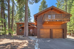 A wooden cabin with a balcony, a garage, and a stone pathway. - Spacious 5BR Carnelian Grand Retreat, Hot Tub, perfect for the whole family (Carnelian Bay)