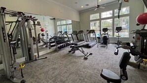 Un gimnasio con máquinas de cardio, equipo de levantamiento de pesas y un espejo.