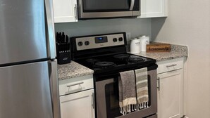 Una cocina moderna con electrodomésticos de acero inoxidable, armarios blancos y una encimera de granito.