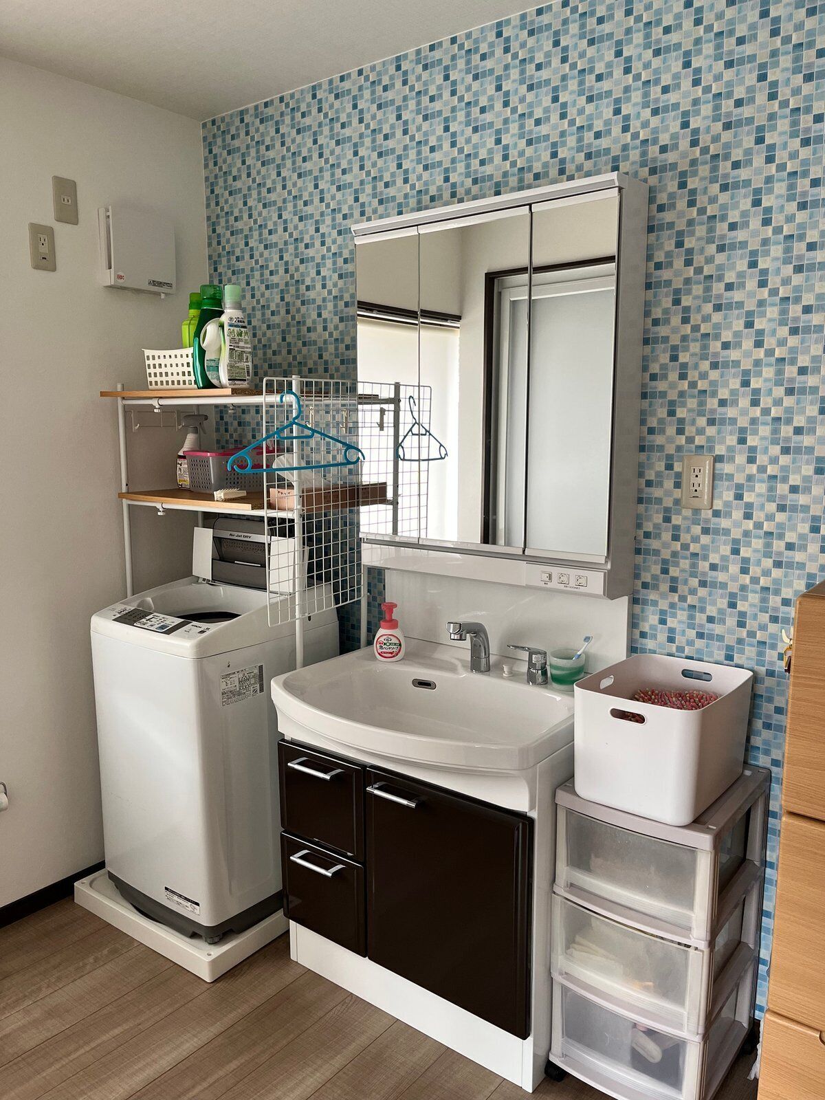 A compact kitchen with a washing machine, a sink, and storage drawers.