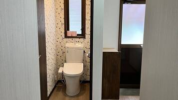 Een kleine badkamer met toilet, wastafel en raam.