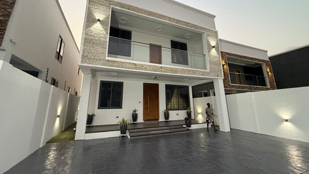 A modern two-story house with a flat roof, a balcony on the upper floor, and a paved driveway. - fransons Homes (Tema)