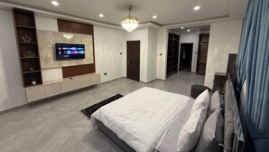 A modern bedroom with a large bed, a TV mounted on the wall, and a walk-in closet. - fransons Homes (Tema)