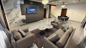 A modern living room with a flat-screen TV, comfortable seating, and a chandelier. - fransons Homes (Tema)