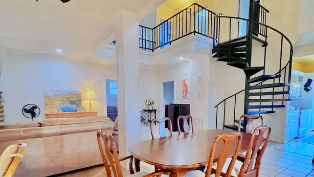 Un vaste espace de vie comprenant une table et des chaises, un escalier et un ventilateur de plafond.