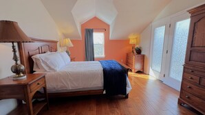 Une chambre à coucher comprenant un lit, des tables de chevet en bois, une commode et un ventilateur de plafond.