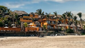 A beachfront hotel with multiple buildings, palm trees, and a sandy beach. - Peña Linda Bungalows (Los Organos)