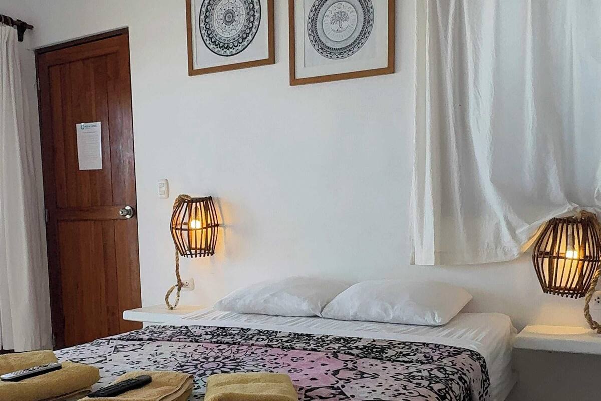 Ein Schlafzimmer mit einem Bett, zwei Wandlampen, einer Tür und zwei gerahmten Wandbildern.