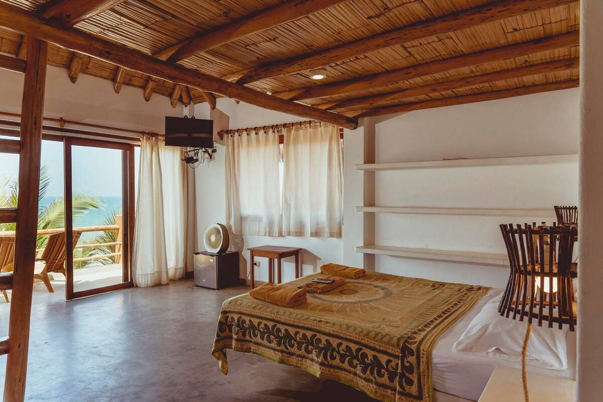 Ein Zimmer mit Bett, Fernseher, Ventilator und Meerblick.