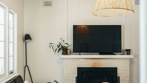 Una sala de estar con chimenea, televisor, sofá, mesa de centro y lámpara colgante.