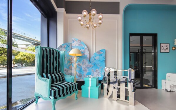 A modern interior with a teal armchair, a lamp, and a large abstract painting.