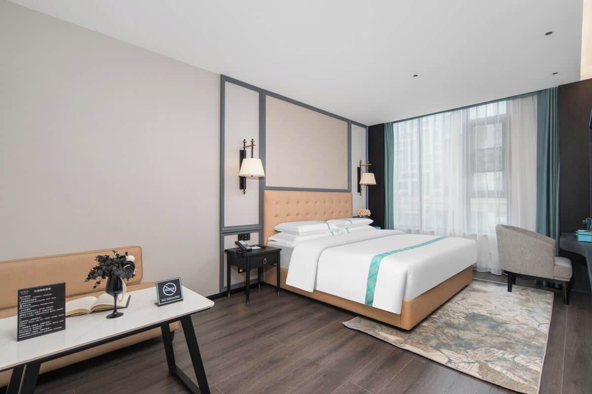 Una habitación de hotel moderna con una cama grande, mesitas de noche, un escritorio y una silla.