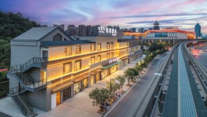 A modern hotel with a multi-story structure, a covered outdoor area, and a view of a busy highway. - Xana Hotel Guilin Wuyue Square  Branch (Guilin)