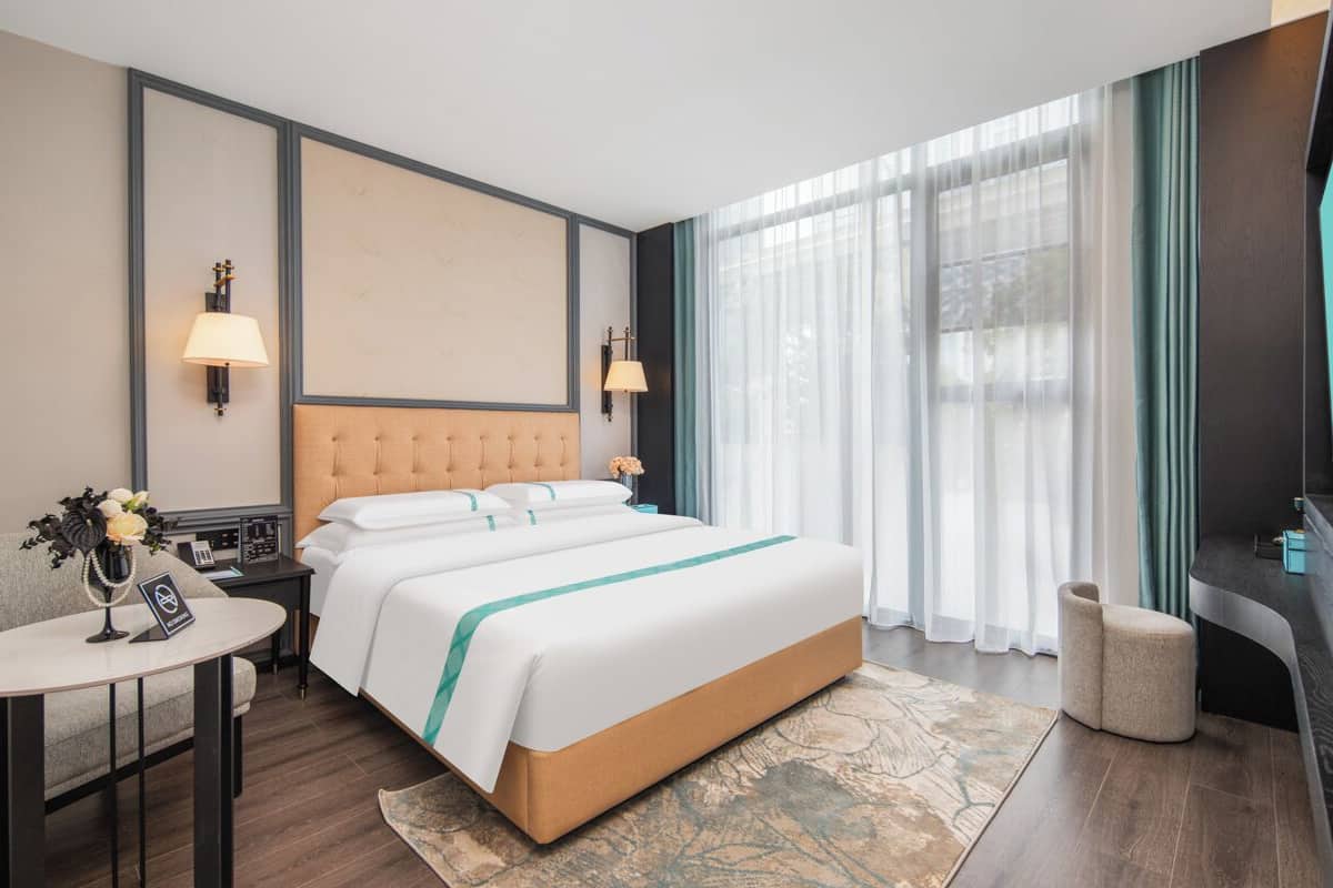 Una habitación de hotel con una cama grande, mesitas de noche, un escritorio y una televisión.