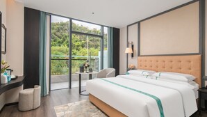 A modern hotel room with a large bed, a desk, a chair, and a balcony with a view of greenery. - Xana Hotel Guilin Wuyue Square  Branch (Guilin)
