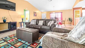 A living room with a brown leather sofa, a patterned armchair, a coffee table, and a TV mounted on the wall. - Spring Hill Serenity:Cozy Escape (Spring Hill)