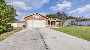 A single-story house with a garage, a front yard, and a clear sky. - Spring Hill Serenity:Cozy Escape (Spring Hill)