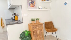 Een moderne keuken met een spoelbak, fornuis en een houten kastje met twee planten in potten.