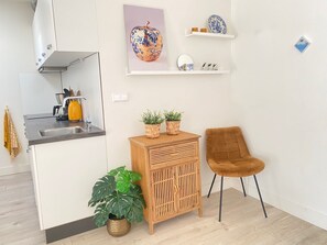 Eine moderne Küche mit Spüle, Herd und einem Holzkabinett mit zwei Blumentöpfen.