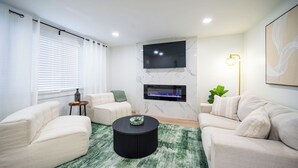Una sala de estar moderna con chimenea, dos sofás, una mesa de centro y una lámpara de pie.
