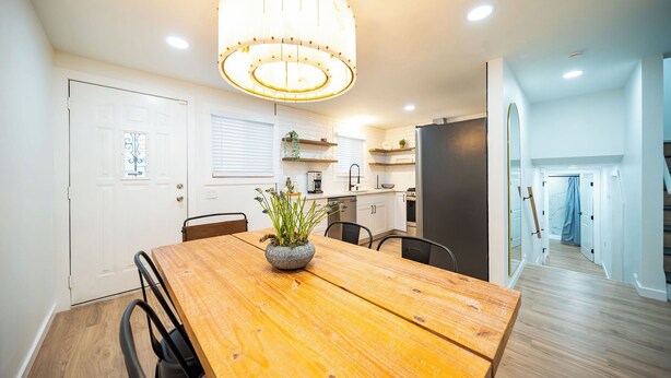 Una cocina moderna con armarios blancos, una mesa de comedor de madera y una araña.