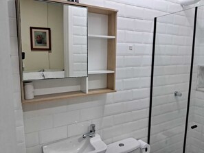 A bathroom with a white sink, a mirror, and a glass shower enclosure. - Botafogo, Rio de Janeiro | Apartment with a view of Sugarloaf Mountain   (Rio de Janeiro)