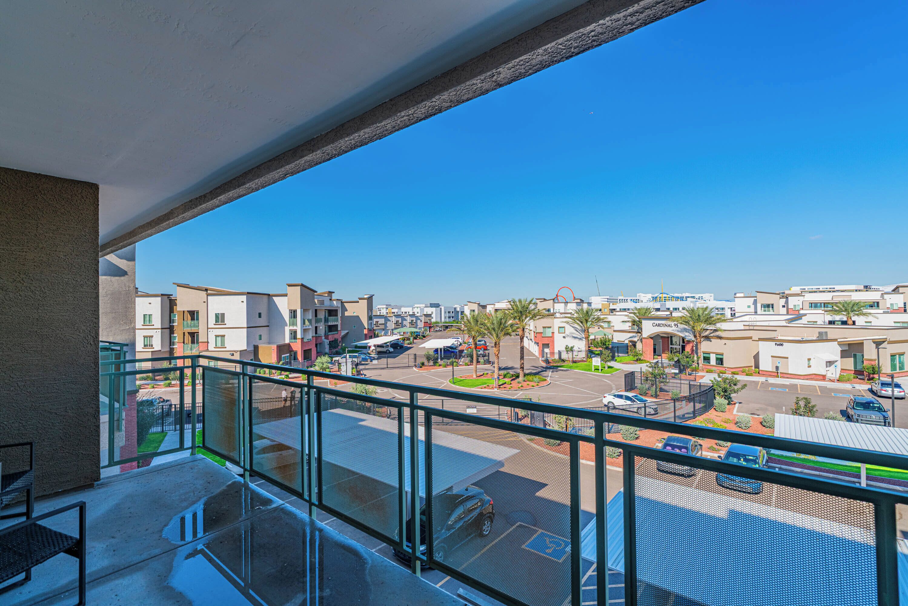 A balcony with a clear view of a parking lot and buildings in the background.