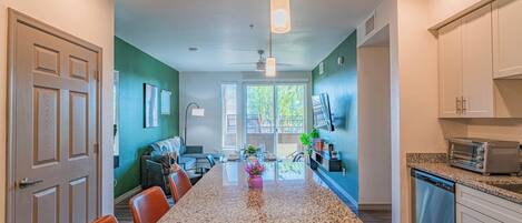 A kitchen with a granite countertop, white cabinets, and a built-in dishwasher.