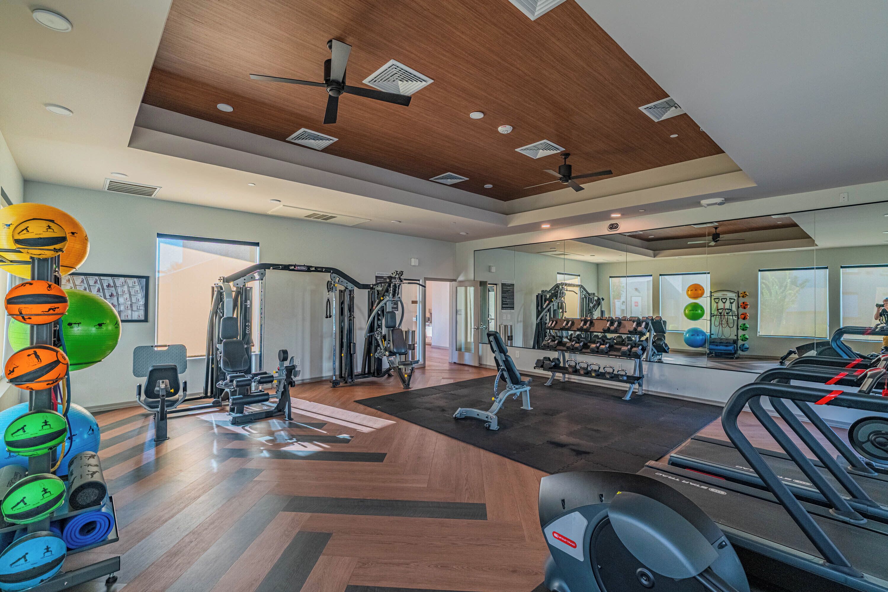 A gym with exercise equipment, treadmills, and a mirror wall.