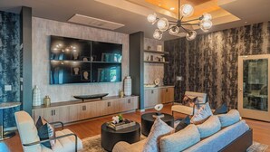 Un salon moderne doté d’un grand téléviseur à écran plat, d’un canapé, d’une table basse et d’un coin repas avec une table à plateau en verre.