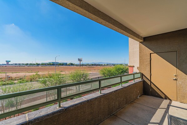 A balcony with a view of a sports field and distant buildings.
