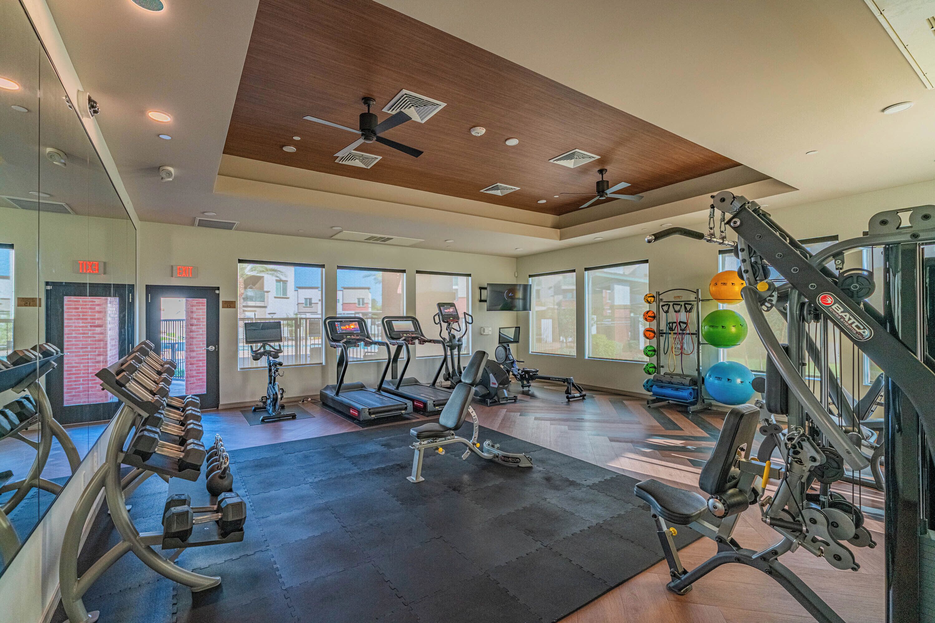 Un gimnasio con cintas de correr, elípticas, bancos de pesas y pesas sueltas.