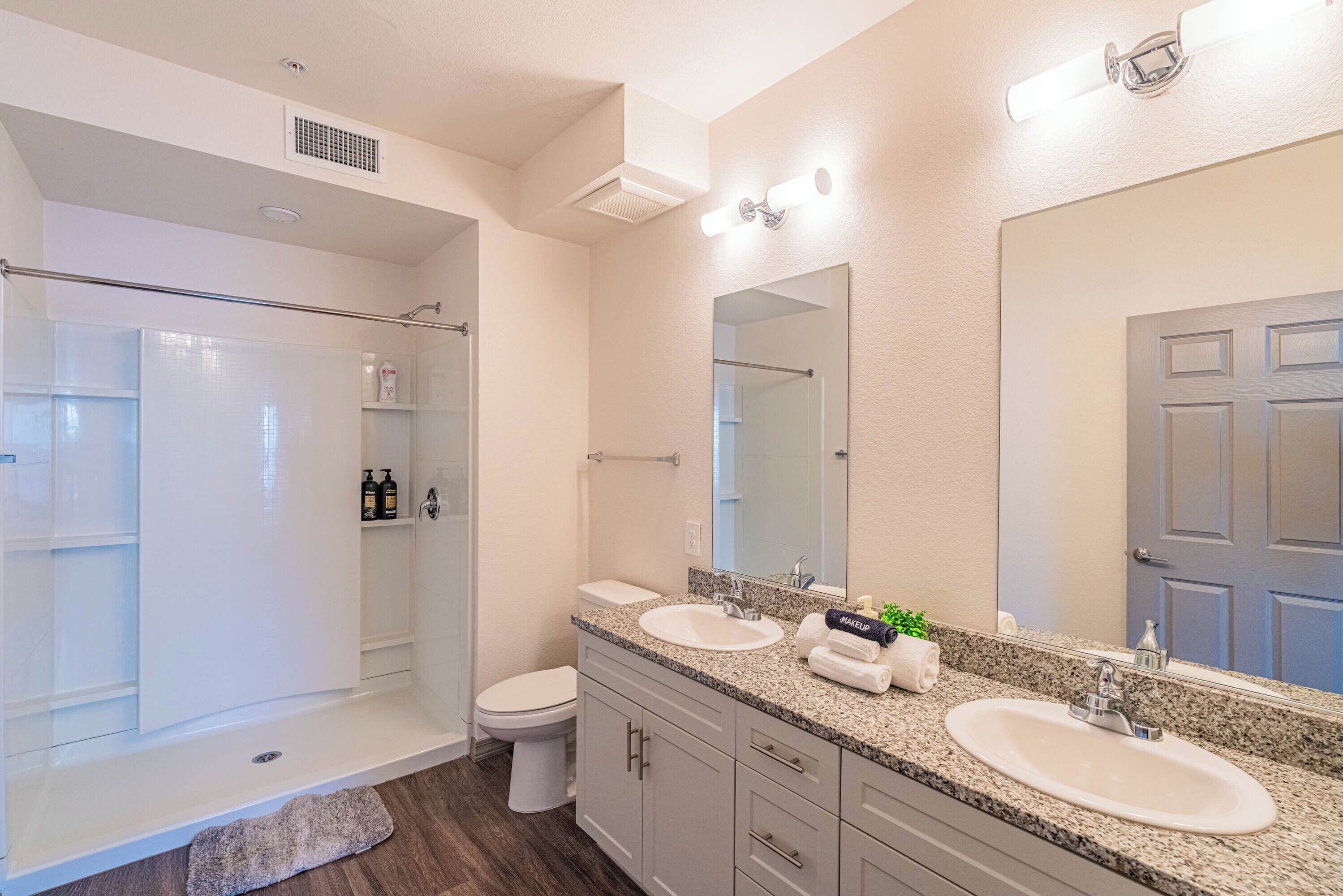 Une salle de bain moderne avec une douche à l’italienne, des toilettes, un lavabo et un grand miroir.