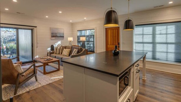 A spacious living area with a large island, a sofa set, and a dining table.