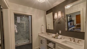 A modern bathroom with a glass shower enclosure, a large mirror, and a vanity with two sinks.