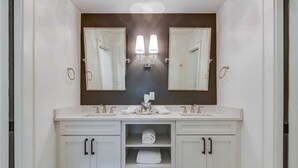 A bathroom with two sinks, a large mirror, and a towel rack.