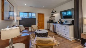 A modern living room with a sofa, a coffee table, and a dining area with a kitchen counter and microwave.