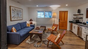 A compact living space with a sofa, chairs, a coffee table, and a kitchen area.