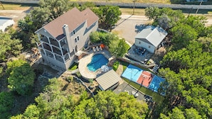 Vista aérea de uma propriedade residencial com piscina, quadra de basquete e uma casa grande com varanda.