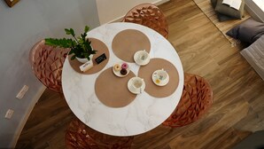 A round table with a white marble top, surrounded by woven placemats, a potted plant, and a small plate with a drink. - Zen Loft - A Peaceful Retreat Minutes from St Julians and Sliema  (Is-Swieqi)