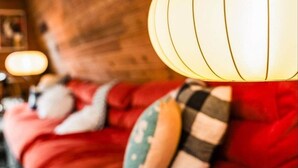 A cozy room with a wooden wall and a red sofa with patterned cushions. - The Mod Lodge, Retro Sunriver Cabin Vibes! (Sunriver)