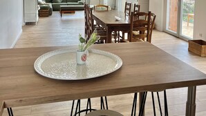 Un vaste espace de vie comprenant une table à manger, un canapé et offrant une vue sur la verdure environnante.