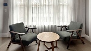 A room with a round wooden table and two armchairs, large windows with sheer curtains, and a decorative ceiling. - The Edward Residences Quiet Luxury (North Sydney)