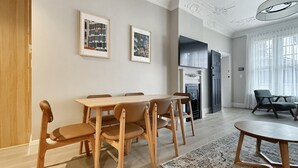 A modern living room with a wooden dining table, chairs, a fireplace, and a TV. - The Edward Residences Quiet Luxury (North Sydney)
