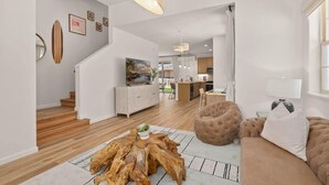 Ein modernes Wohnzimmer mit einem Holztisch, einem braunen Sofa und einem Essbereich im Hintergrund.
