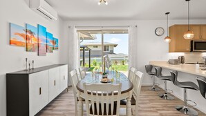 A modern kitchen with a dining area, featuring a large window, a dining table with chairs, and a kitchen counter with bar stools. - @ML Ocean view, Golf, Gazebo and BBQ, we have all! (Waianae)