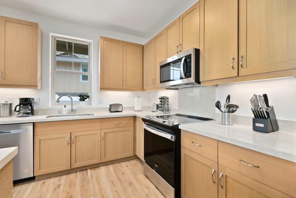 Una cocina moderna con armarios de madera, electrodomésticos de acero inoxidable y encimera blanca.