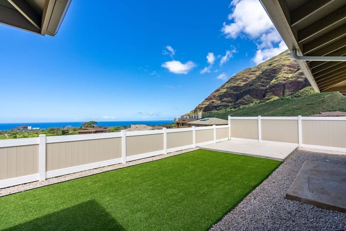 A balcony with a view of the ocean and a hillside.