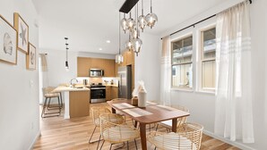 Eine moderne Küche mit Holzschränken, einer zentralen Kochinsel und einem Essbereich mit Holztisch und Korbstühlen.